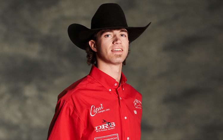 Kade Bruno vistiendo una camisa roja abotonada y un sombrero de vaquero.